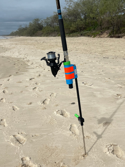 Green Surf fishing rod holder with rod and reel on sandy beach