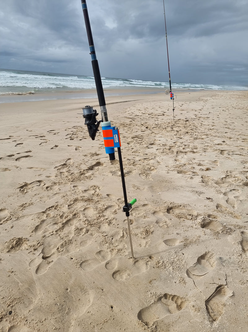 Fibreglass and stainless steel fishing rod holder on sandy beach with ocean in the background