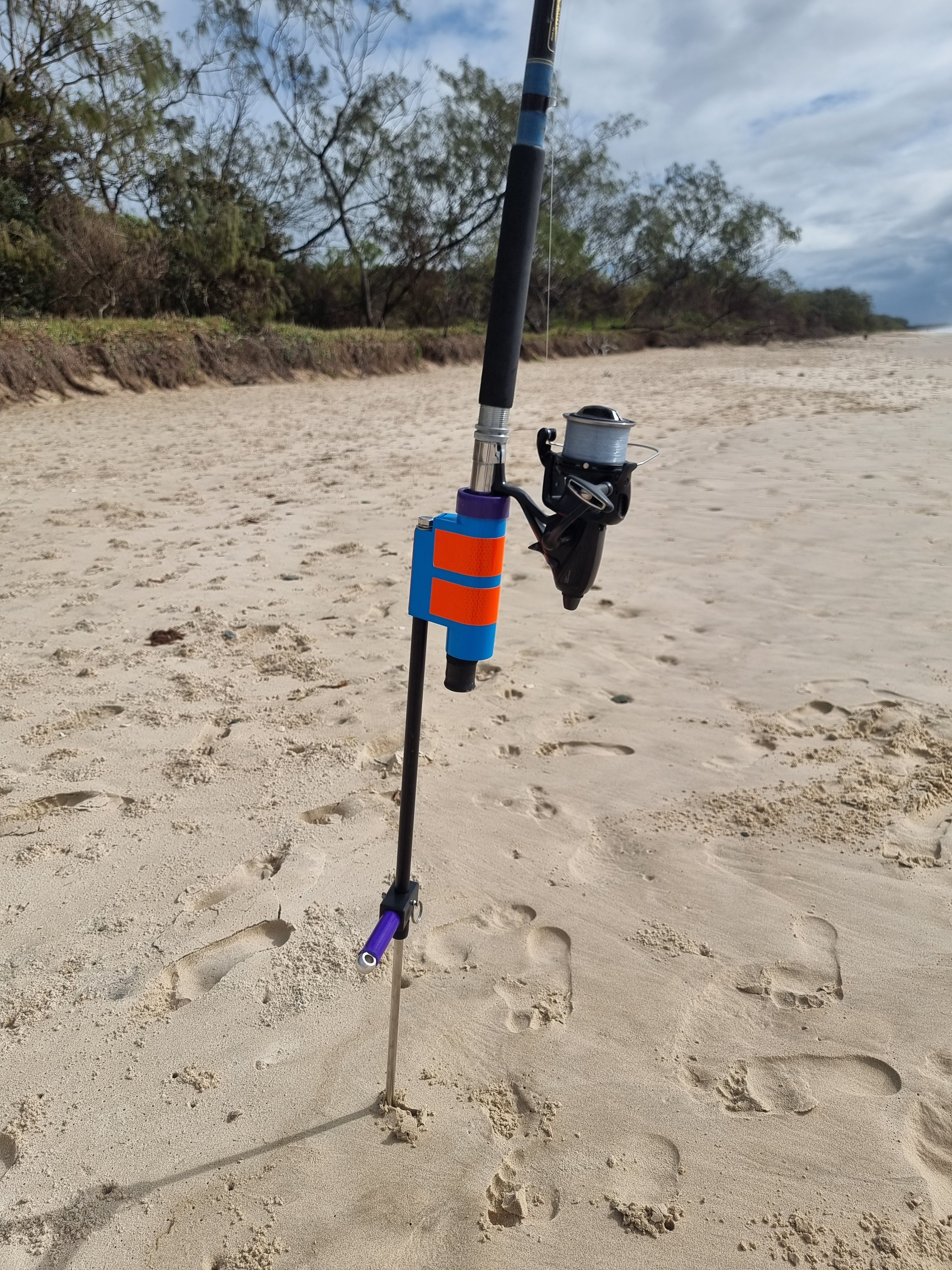 Fishing rod with baitrunner in fibreglass fishing rod holder on sandy beach