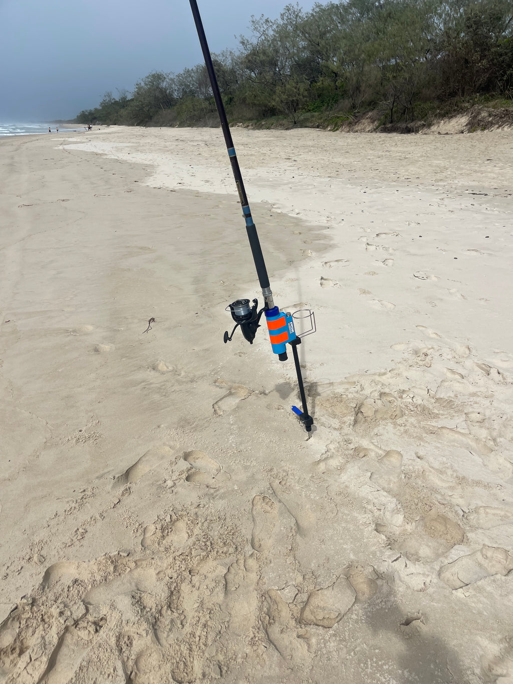 Fishing rod holder with drinks holder on sandy beach