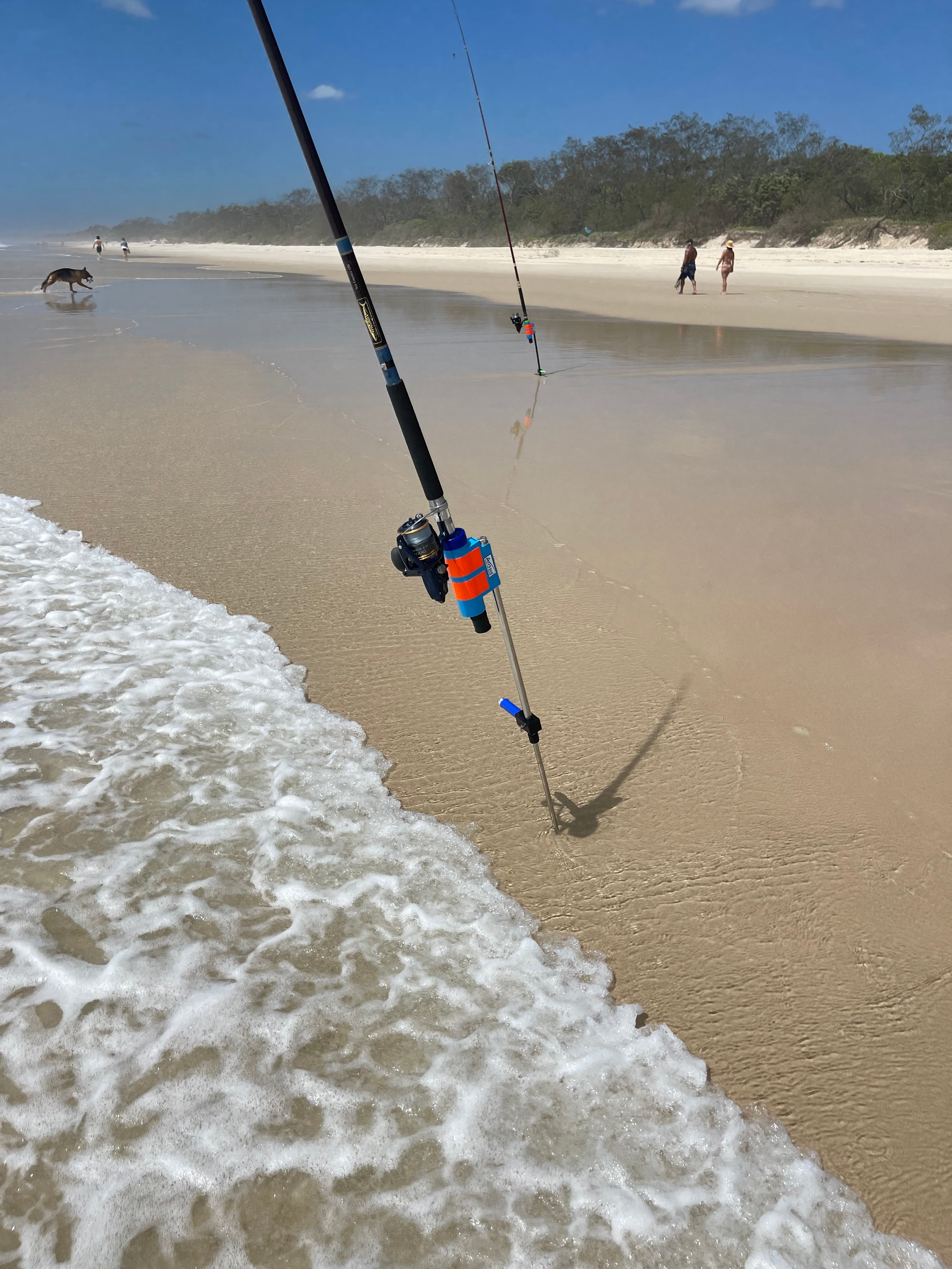Surf fishing rods and reels in rod holders on beach with waves