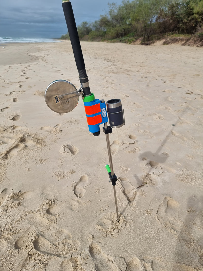 Fishing rod with colorful reel in Aussie Rod Holder with drinks holder on sandy beach