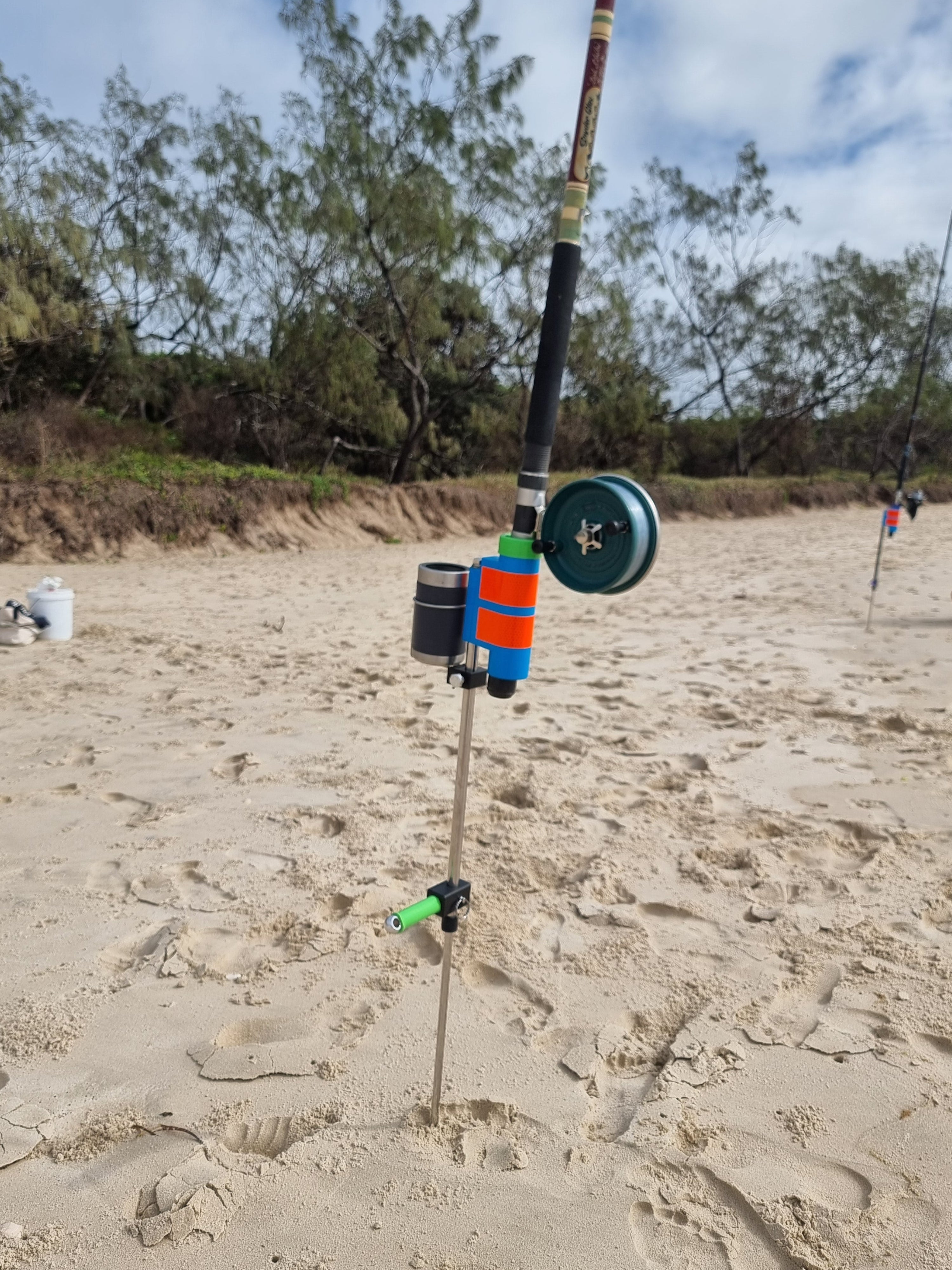 Fishing rod with reel on a sandy beach with fishing rod holder and drinks holder