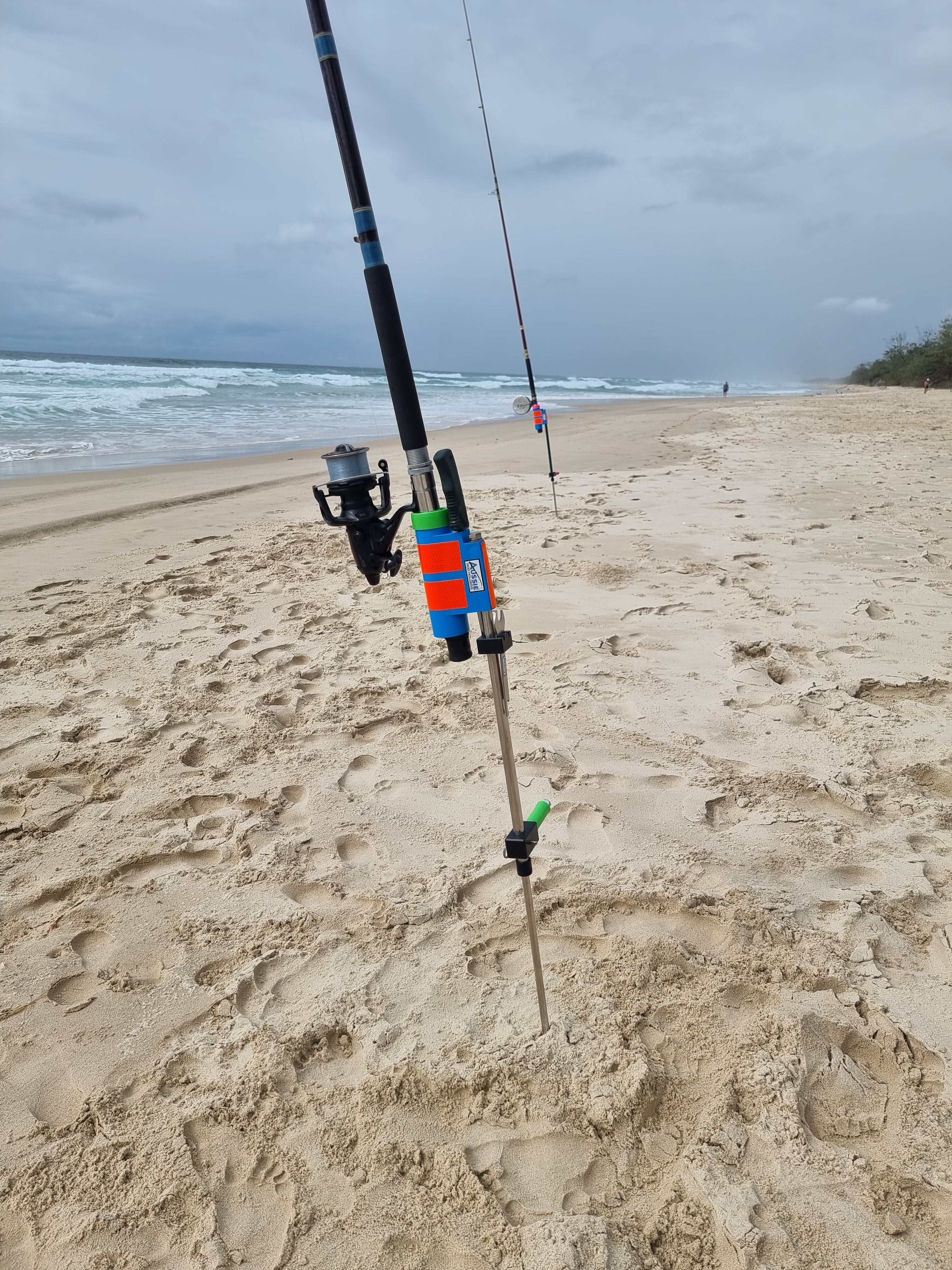 Rod and baitrunner in stainless steel rod holder with fishing knife on beach