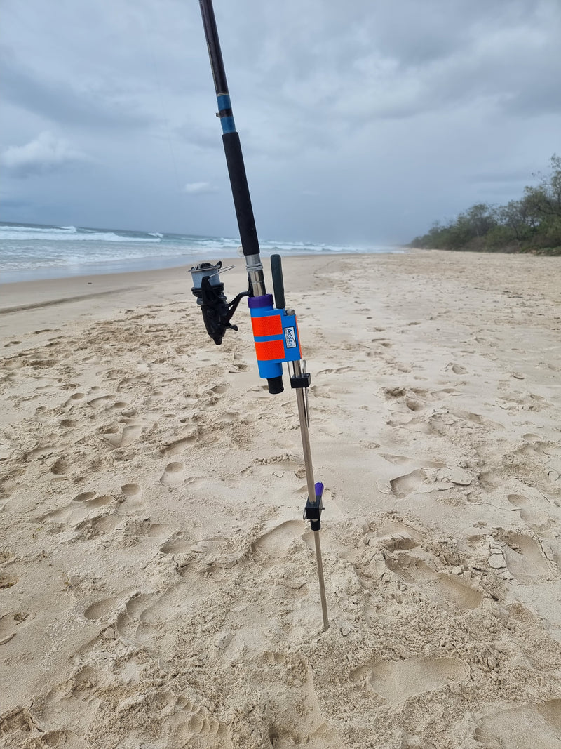 Fishing rod and baitrunner in stainless steel rod holder on beach with fishing knife.