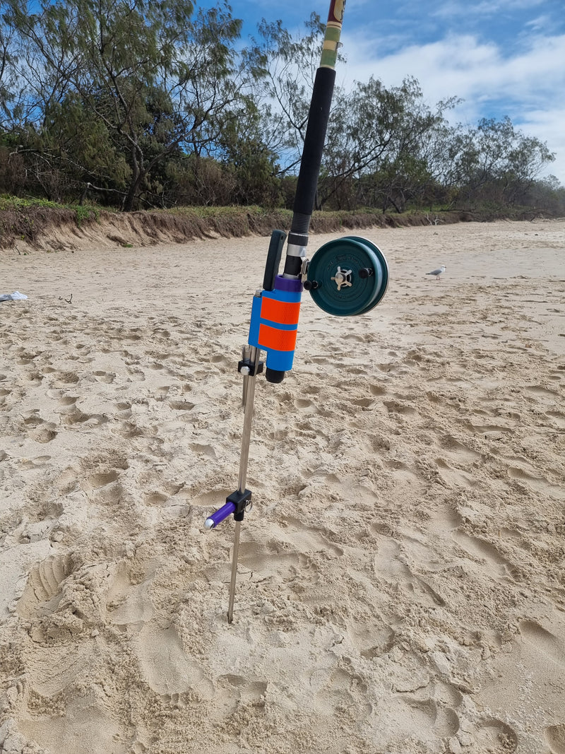 Fishing rod with Alvey reel in stainless steel rod holder on a sandy beach 