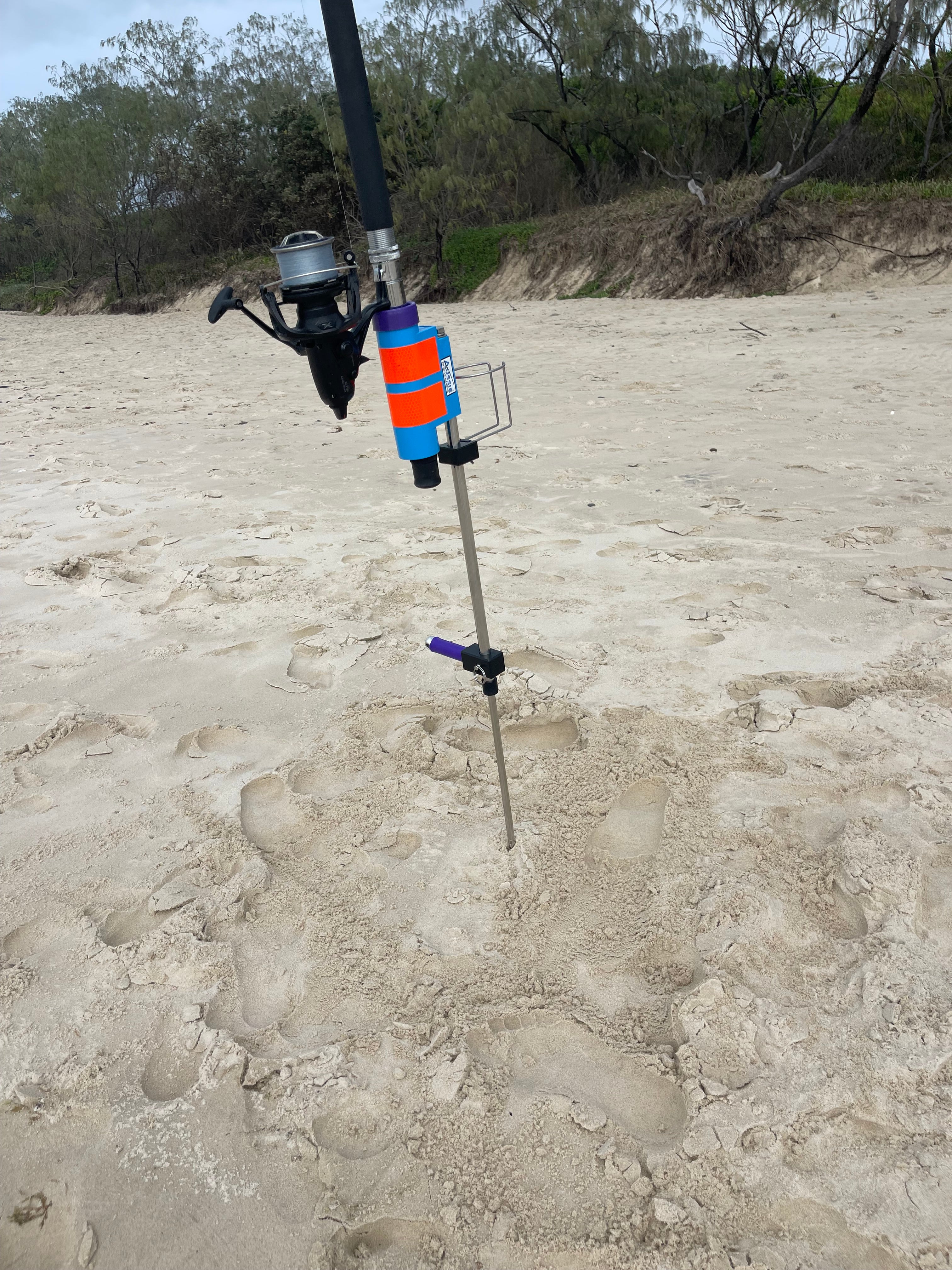 Fishing rod with reel in rod holder with sand spike on a sandy beach