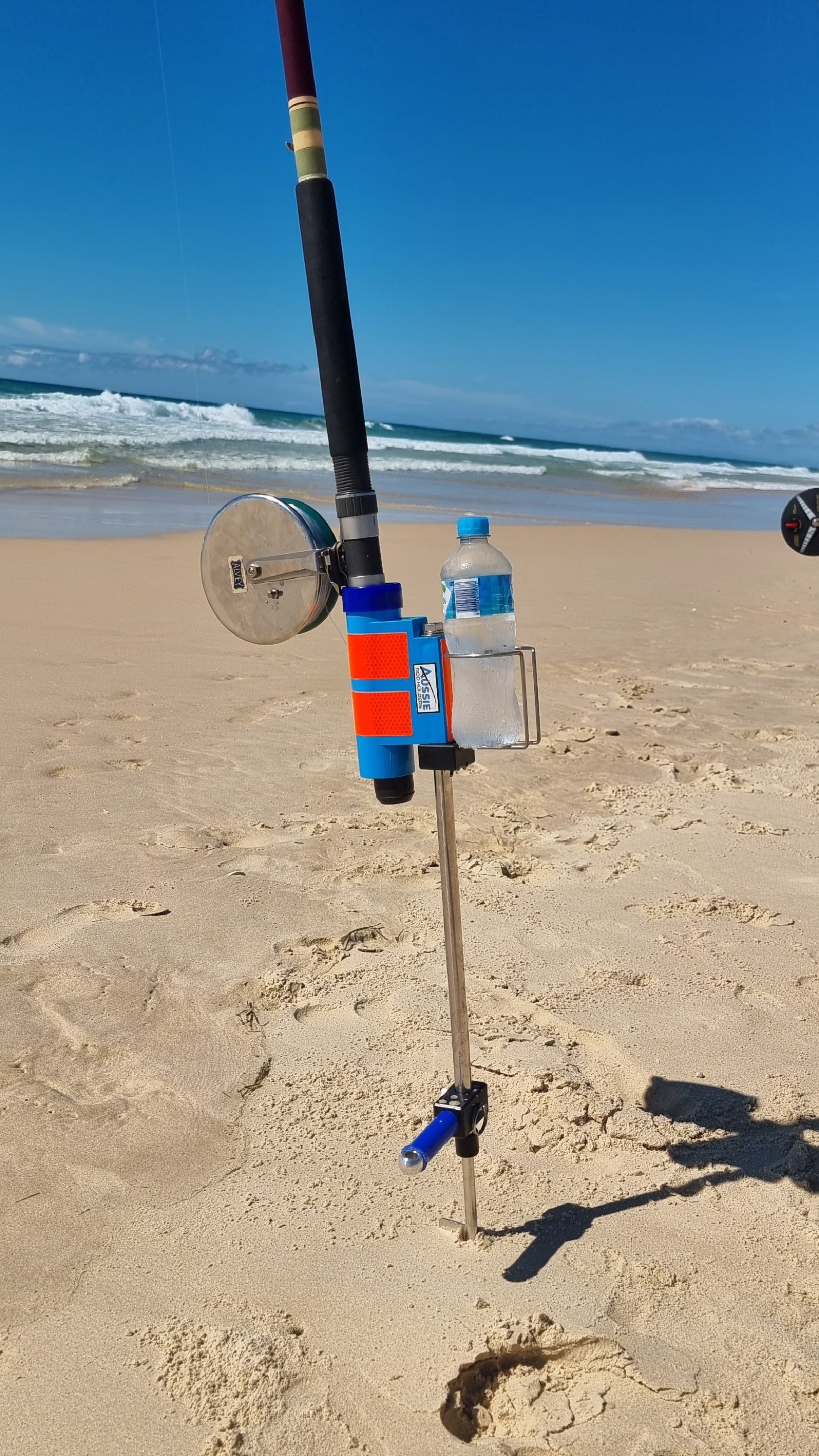 Fishing rod and reel with fishing rod holder and cup holder on Australian beach