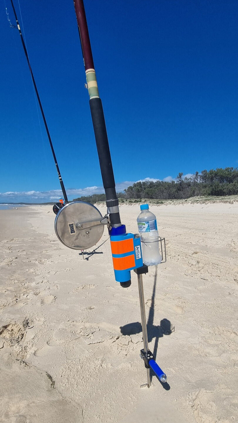 fishing rod and reel in blue fishing rod holder with drinks holder on the sandy beach with blue sky
