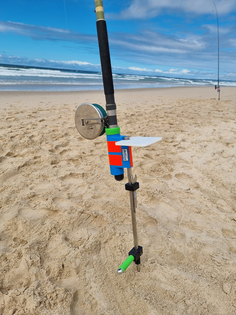 Stainless steel fishing rod holder with bait board on sandy beach with surf in background