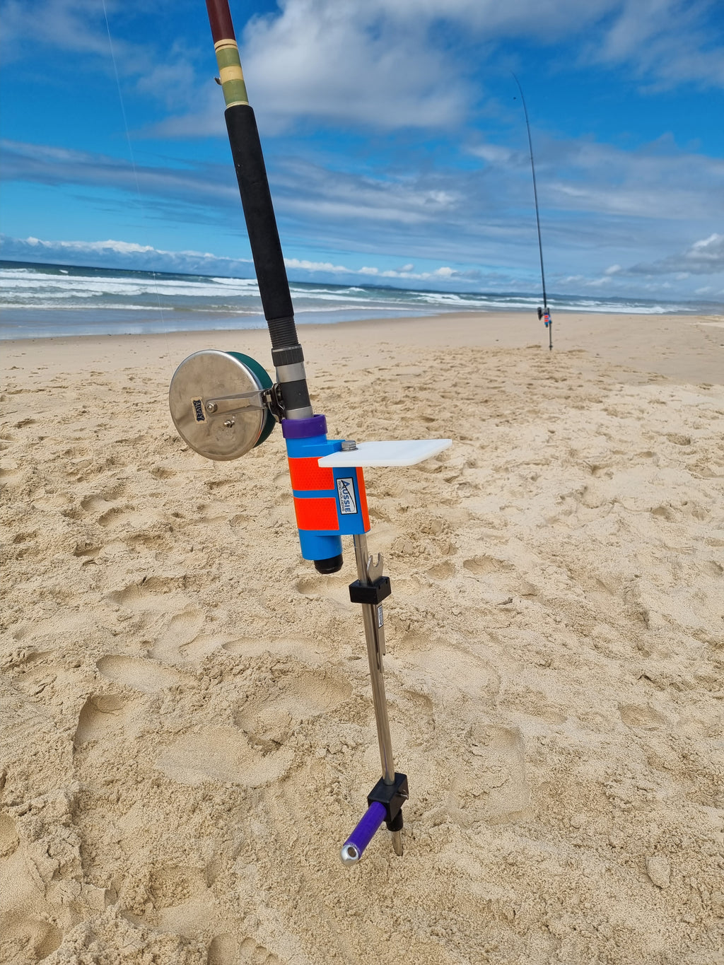 Fishing rod with alvey reel in stainless steel rod holder with bait board at beach