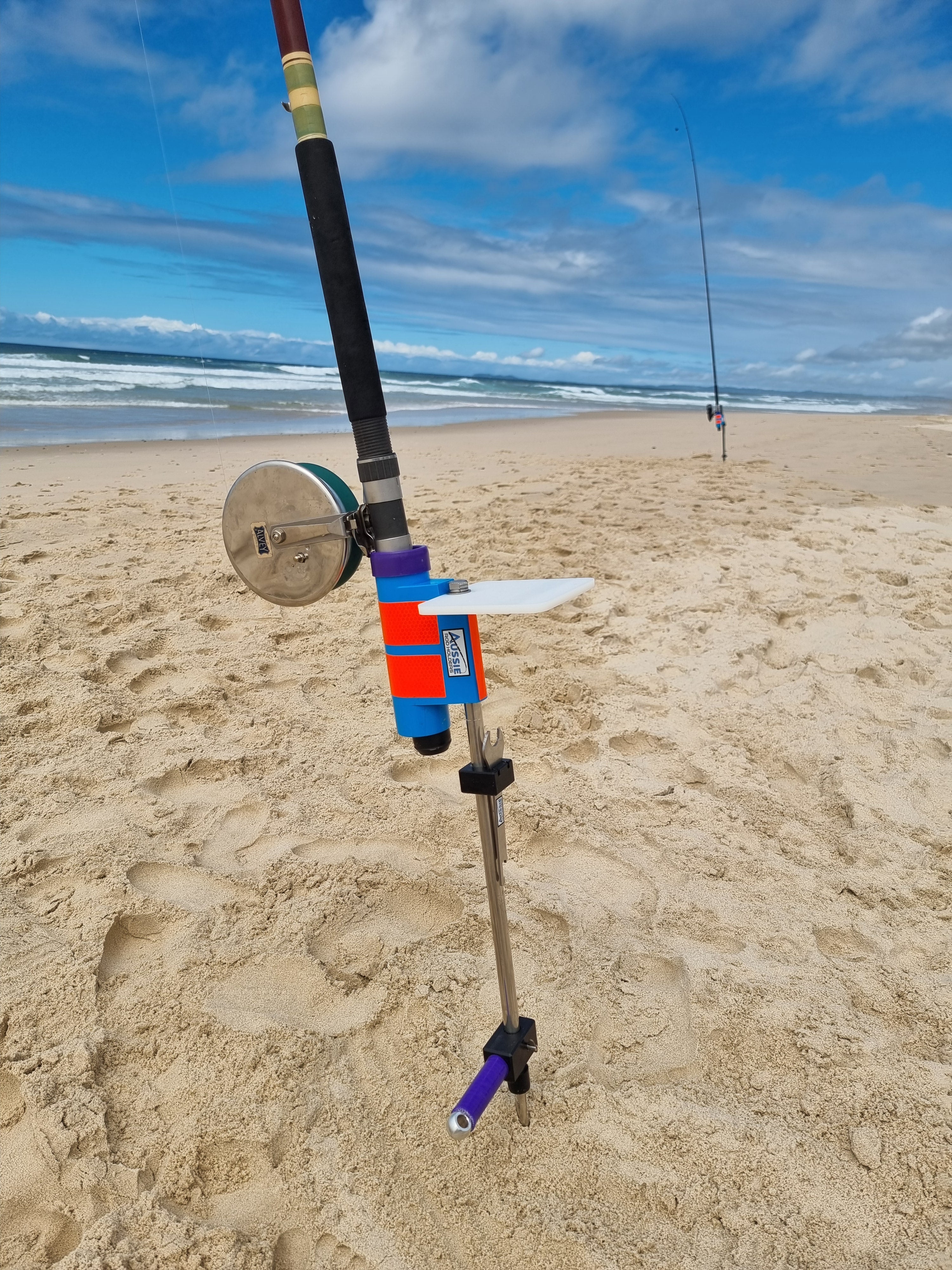 Fishing rod with alvey reel in stainless steel rod holder with bait board at beach